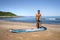 Mężczyzna pompujący na plaży deskę Aqua Marina Beast