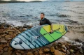 11.6 PRO SUP Gladiator niesiony przez faceta przy skalnym brzegu.webp