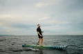 mężczyzna na desce SUP Gladiator Pro stoi stabilnie i płynie po niespokojnej wodzie.webp