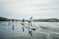 Pompowane deski SUP Gladiator Elite - duża grupa osób na wodzie na tle pięknych trawaistych klifów_half.webp