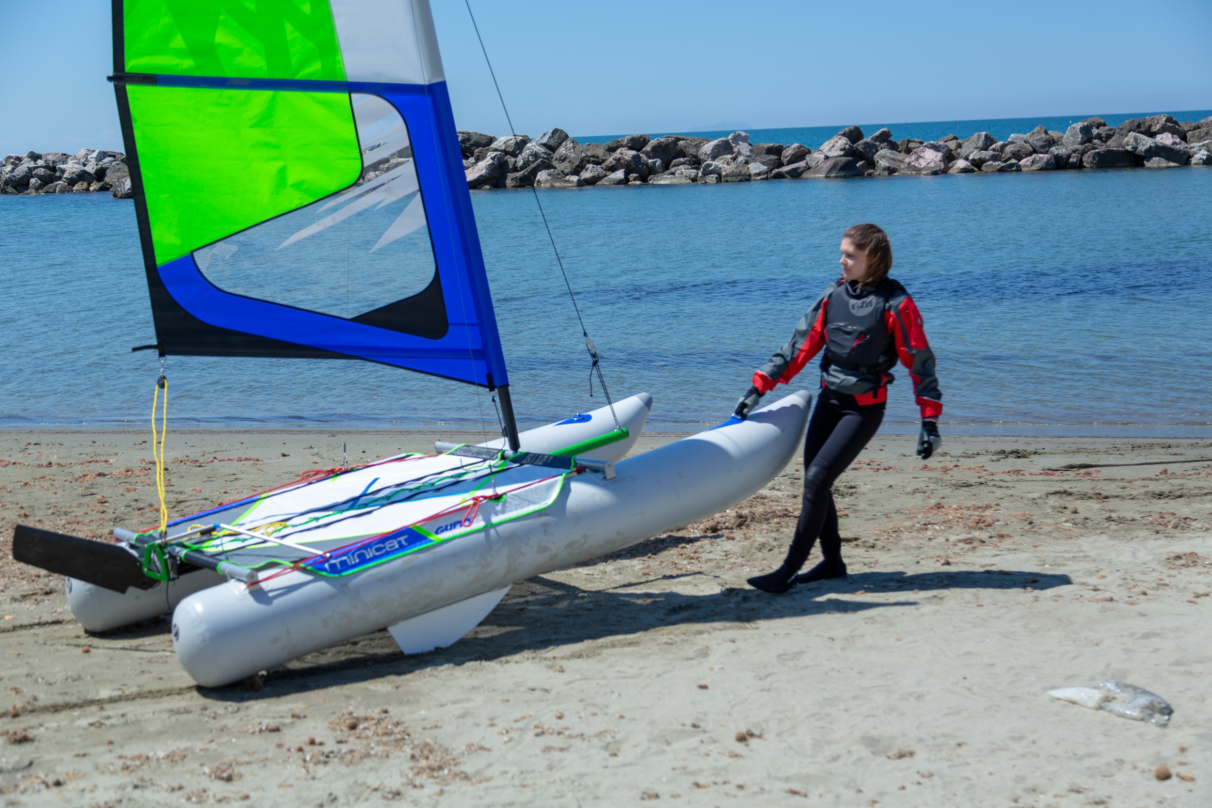 Wodowanie Minicat Guppy - kobieta ciągnie go po plaży do wody.